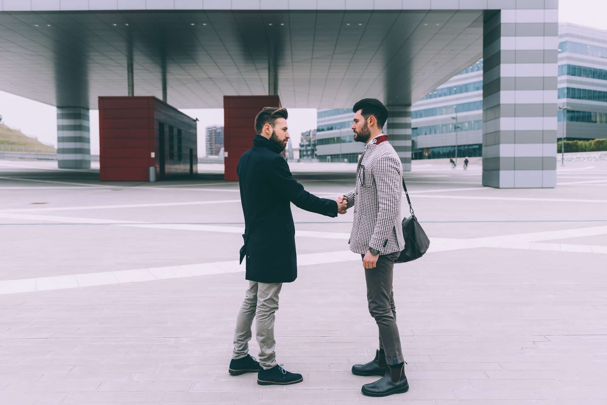 two young business men outdoor shaking hands